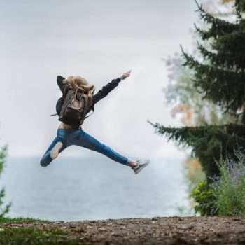 Woman jumping for joy alone in the middle of a forest