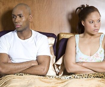 Couple sitting up in bed, both looking away