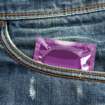 violet condom in the front pocket of a pair of jeans