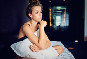 Beautiful young woman with relationship difficulties standing sad in the bed