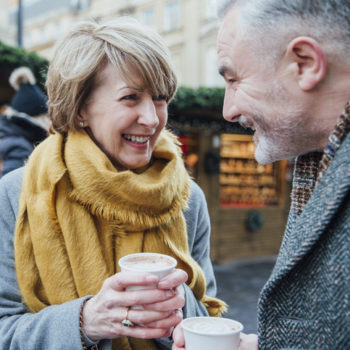 mature couple smiling at one another holding a cup of coffee