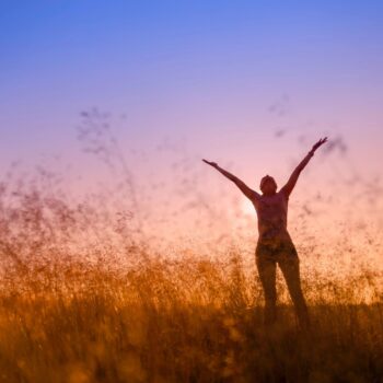 woman raising hands in a field