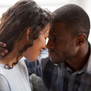 Close up of loving mixed race couple hug relaxing at home together looking in eyes, tender black man and woman embrace having intimate close moment, spend time cuddling enjoy each other company