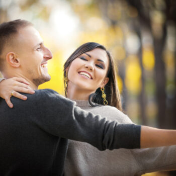 Portrait of a happy asian and caucasian couple of lovers on a date dancing in autumn park.