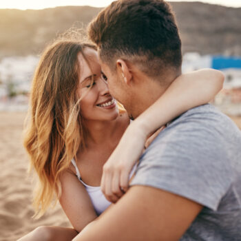 Romantic young couple sitting together on a sandy beach