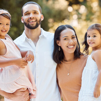 Family, portrait and nature with a couple and their kids bonding in a natural garden in summer. Mother, father and daughter sisters or siblings bond with love, care and affection outside